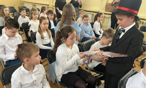 uczniowie w odświętnych strojach siedzą w rzędach na sali