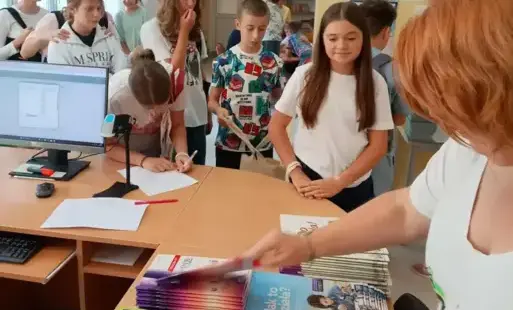 Uczniowie w bibliotece odbierają podręczniki