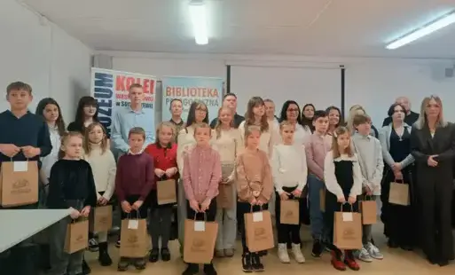 uczestnicy konkursu, nagrodzeni trzymają w ręku torby z nagrodami